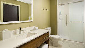 A modern bathroom with a large mirror, a sink, a toilet, and a glass-enclosed shower. - Home2 Suites by Hilton Hattiesburg (Hattiesburg)