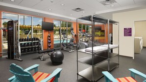 A gym with exercise equipment, a pool, and a sheltered area with chairs. - Home2 Suites by Hilton Hattiesburg (Hattiesburg)