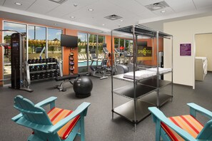A gym with exercise equipment, a pool, and a sheltered area with chairs. - Home2 Suites by Hilton Hattiesburg (Hattiesburg)
