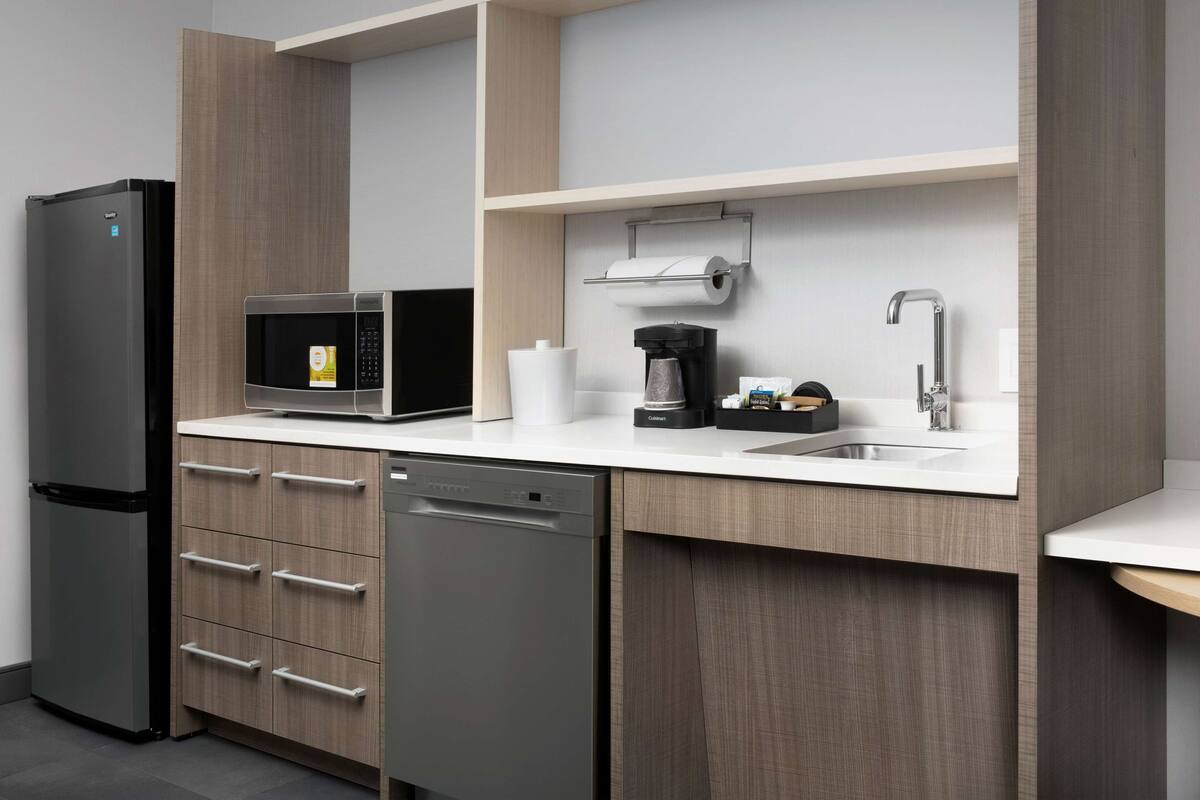 A modern kitchen with a built-in refrigerator, microwave, coffee maker, and dishwasher.