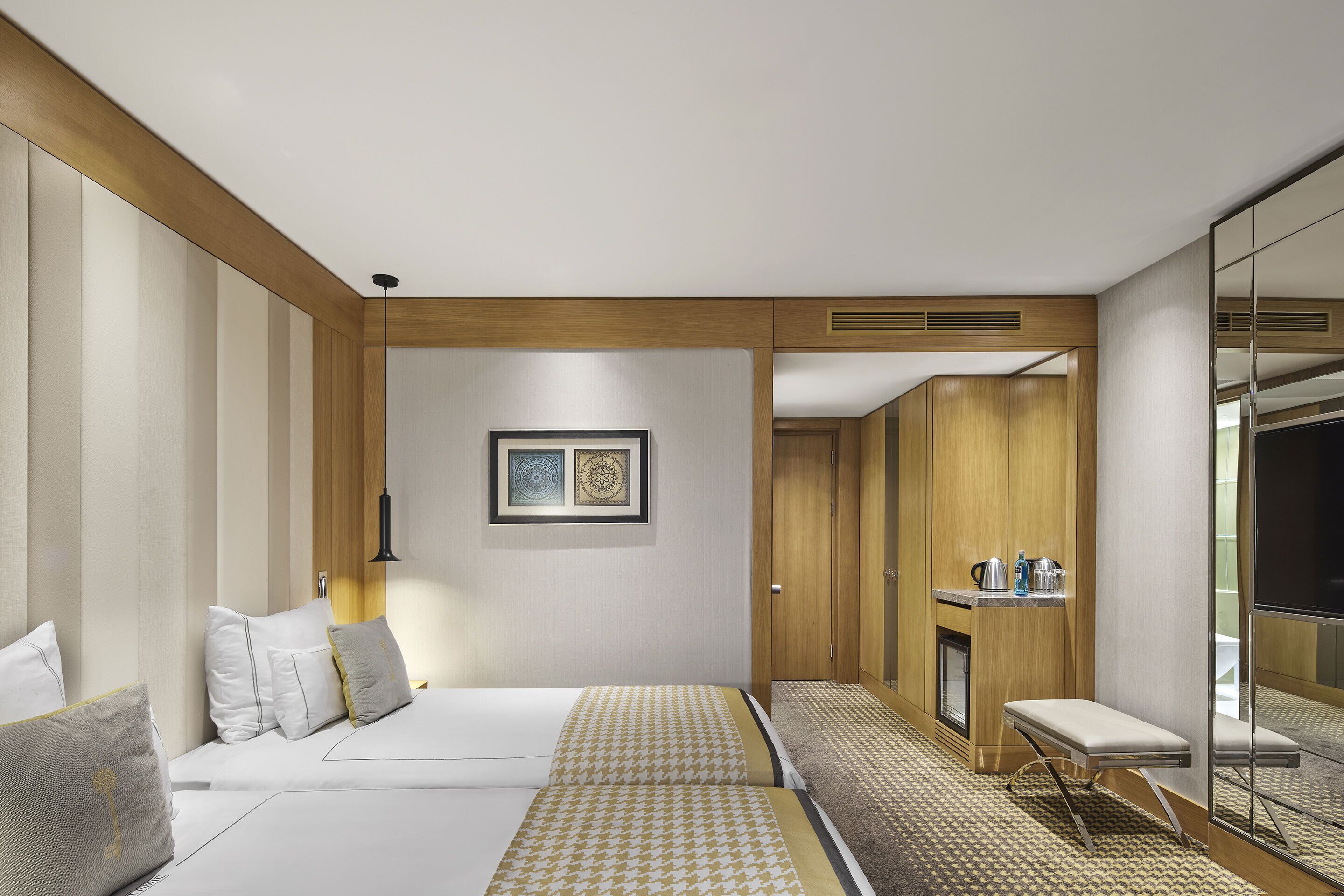 Quarto de hotel com cama, mesa de cabeceira e espelho.