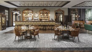 Un restaurante con zona de bar, diversas opciones de asientos y suelo estampado.