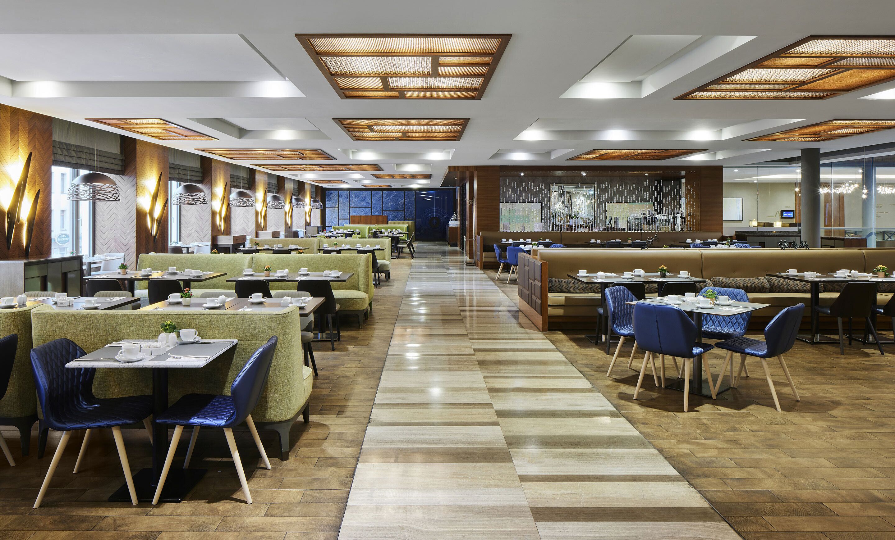 Un restaurante moderno con varias zonas de comedor, incluyendo cabinas y mesas, y un pasillo central.