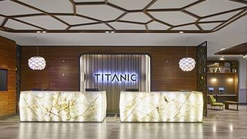 Eine Lobby mit einer Rezeption, einer Wanduhr und einem Schild mit der Aufschrift 'TITANIC'.