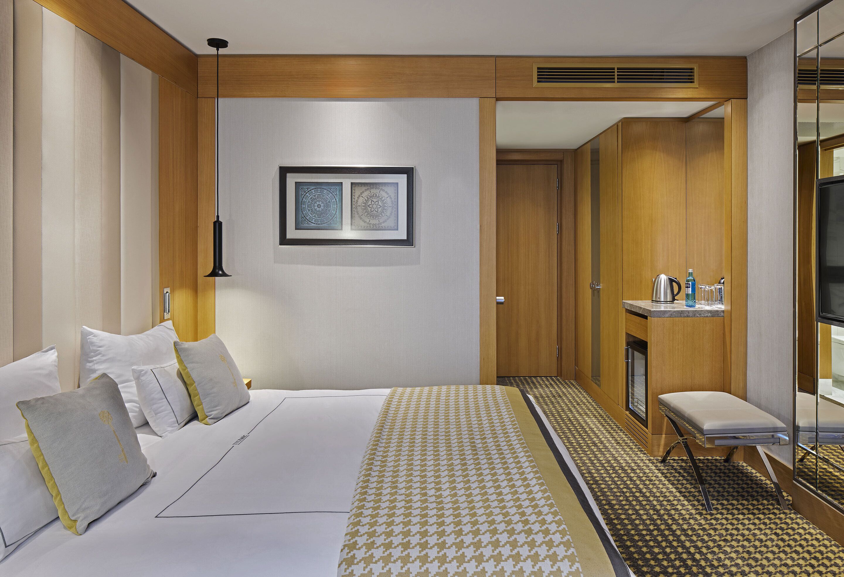 A hotel room with a large bed, bedside tables, a small seating area, and a television.