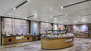 Un moderno vestíbulo de hotel con una zona de buffet central, paneles decorativos en la pared y un piso de madera pulida.