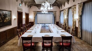 A conference room with a long table, chairs, a projector screen, and a chandelier. - Dell Angelo (Locarno)