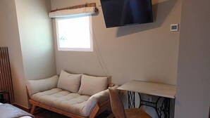 A cozy room with a sofa, a small table, a chair, a TV, and a window with a view. - San Francisco (Ronda)