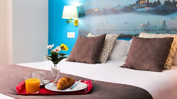 A hotel room with a bed, a tray with breakfast, a vase with flowers, and a wall with a scenic view and text. - San Francisco (Ronda)