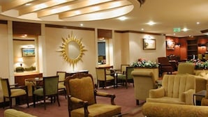 A hotel lobby with a sunburst mirror, multiple seating areas, and a reception desk. - San Francisco (Ronda)