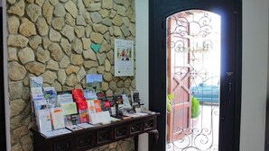 A reception desk with brochures and a stone wall. - San Francisco (Ronda)