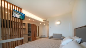 Une chambre d’hôtel avec un lit, une chaise, une télévision, une armoire et une petite table.