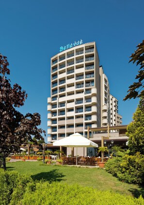 Un hotel de diseño moderno, con varios balcones y un área exterior bien cuidada con mobiliario.