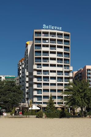 A multi-story hotel with balconies, a sign reading 'Bellevue,' and a beach in the foreground.