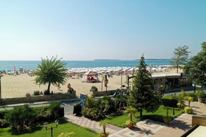 Un hotel frente a la playa con vista al mar, asientos al aire libre y una zona techada.