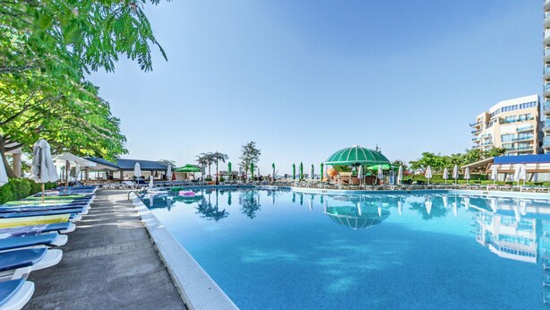 A swimming pool with lounge chairs and umbrellas, surrounded by buildings and trees. - Hotel Sentido Bellevue Beach Sunny Beach (Nessebar)