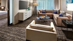Une chambre d’hôtel avec un canapé, une table basse, une télévision, une lampe et un lit.