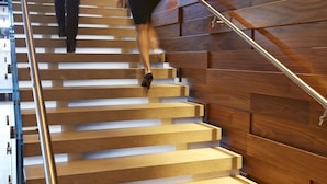 Un escalier en bois avec une rampe métallique, menant à un étage supérieur.