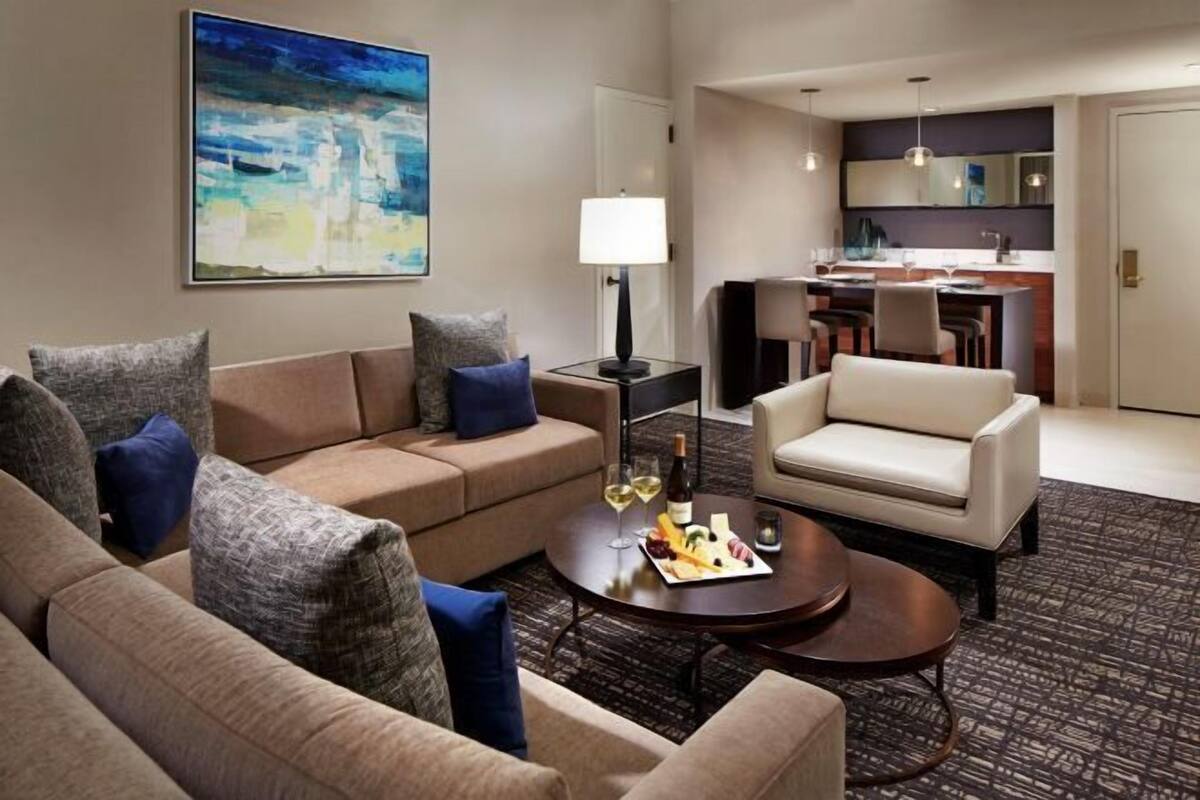 Une chambre d’hôtel avec un canapé, un fauteuil, une table à manger et un tableau au mur.