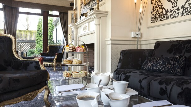 Een luxueuze woonkamer met een zwarte bank, een glazen salontafel en een etagère voor desserts.