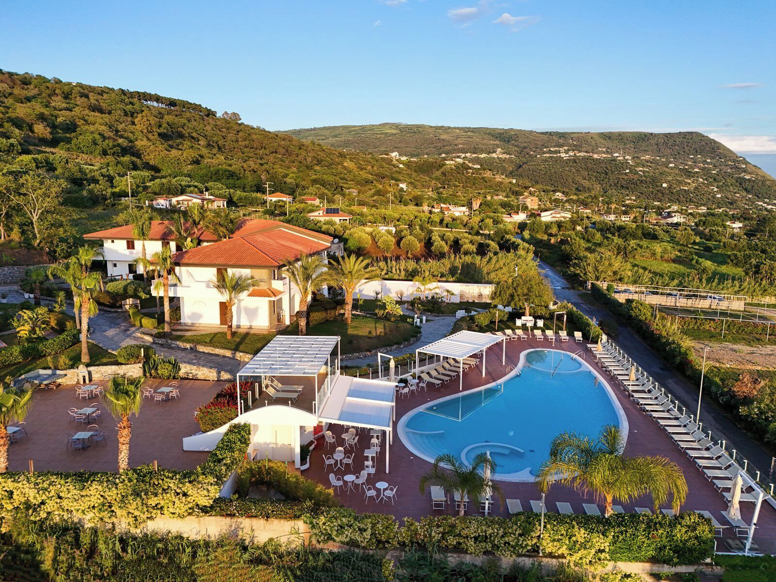 A resort with a swimming pool, lounge chairs, and a view of the surrounding hills.