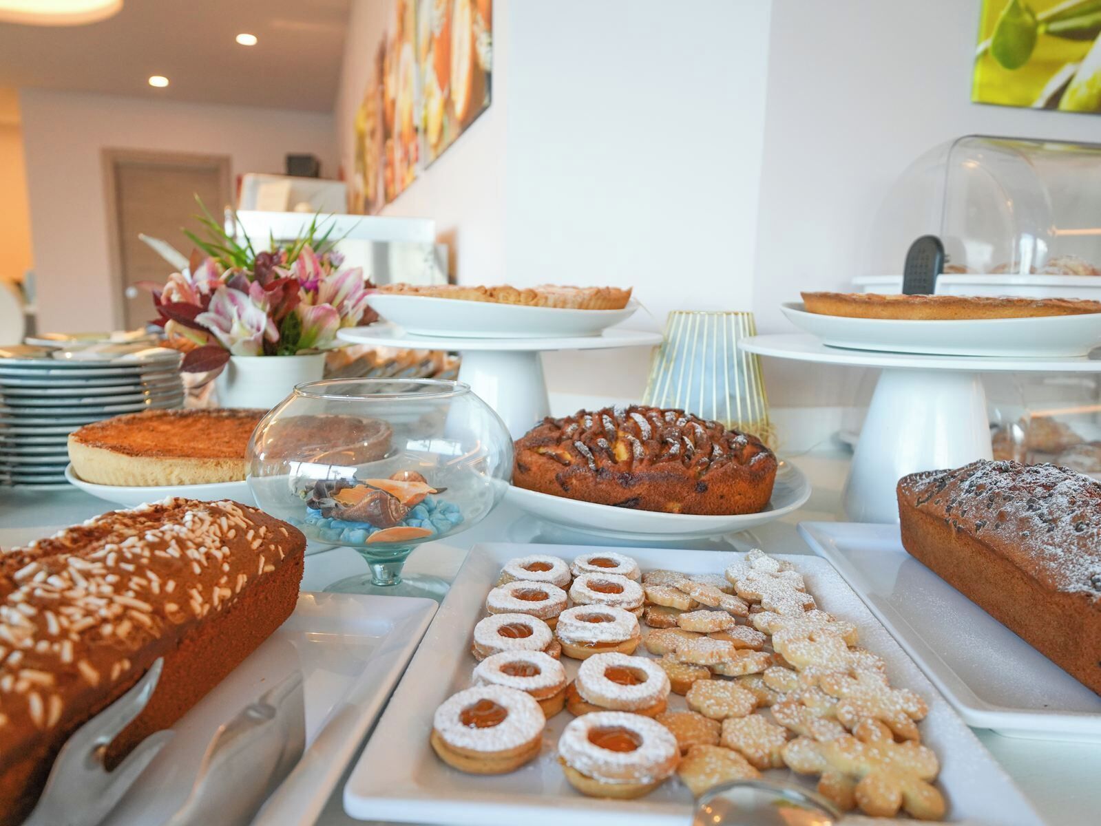 Uma mesa de buffet com diversos produtos de panificação, incluindo bolos, doces e biscoitos.