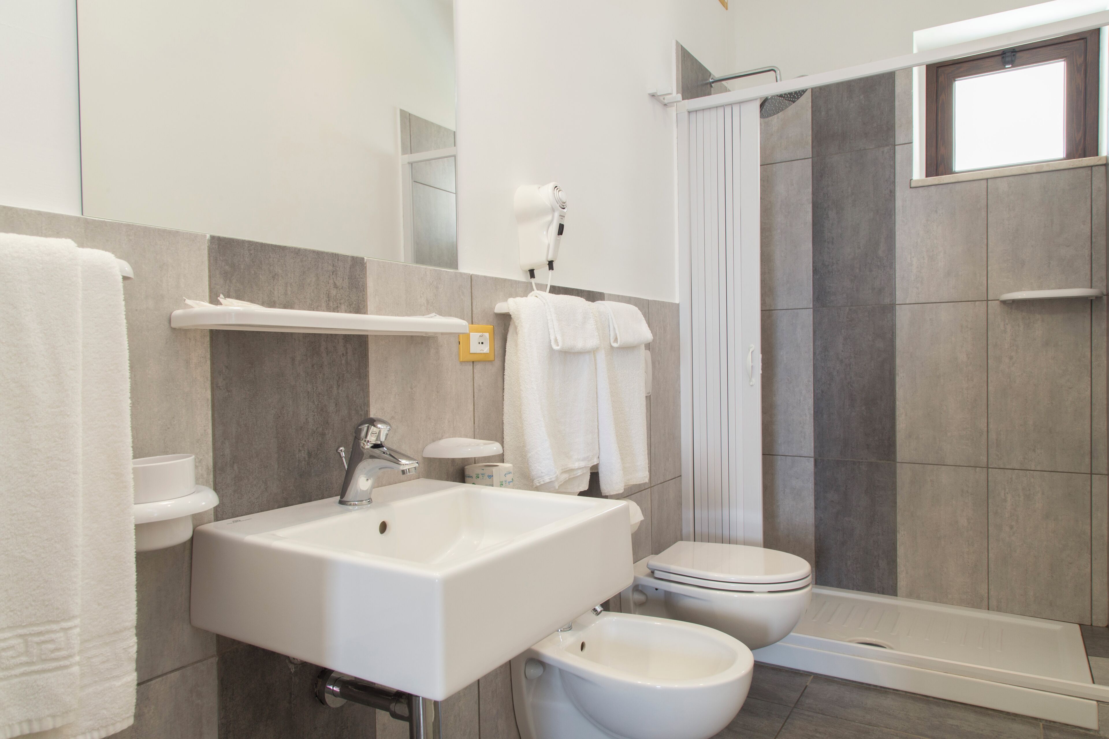 A modern bathroom with a sink, bidet, toilet, and a walk-in shower.