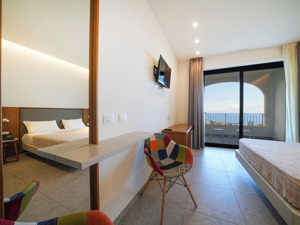 Habitación de hotel moderna con cama, escritorio, una silla colorida y balcón con vistas.