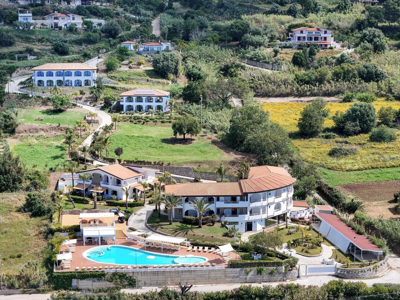 Un gran resort con varias edificaciones, una piscina central y jardines ajardinados que lo rodean.