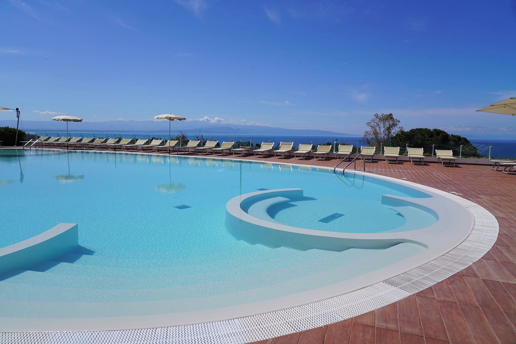 A swimming pool with a clear blue sky and distant mountains.