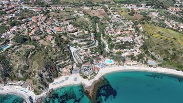 Eine Luftaufnahme einer Küstenstadt mit Strand, Wohngebieten und einem großen Gebäude mit Pool.