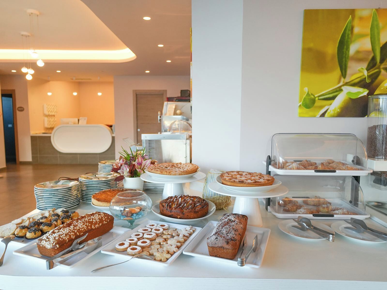 A buffet with various baked goods and pastries, including cakes, pies, and bread, displayed on white plates and stands.