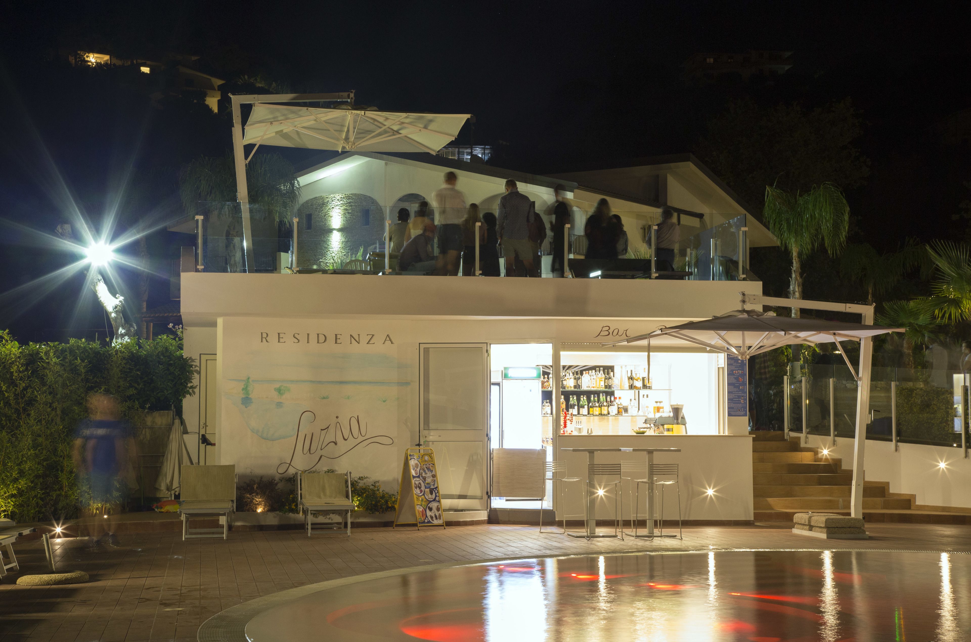 Un espace bar moderne doté d’une piscine, d’un comptoir et de sièges en plein air.