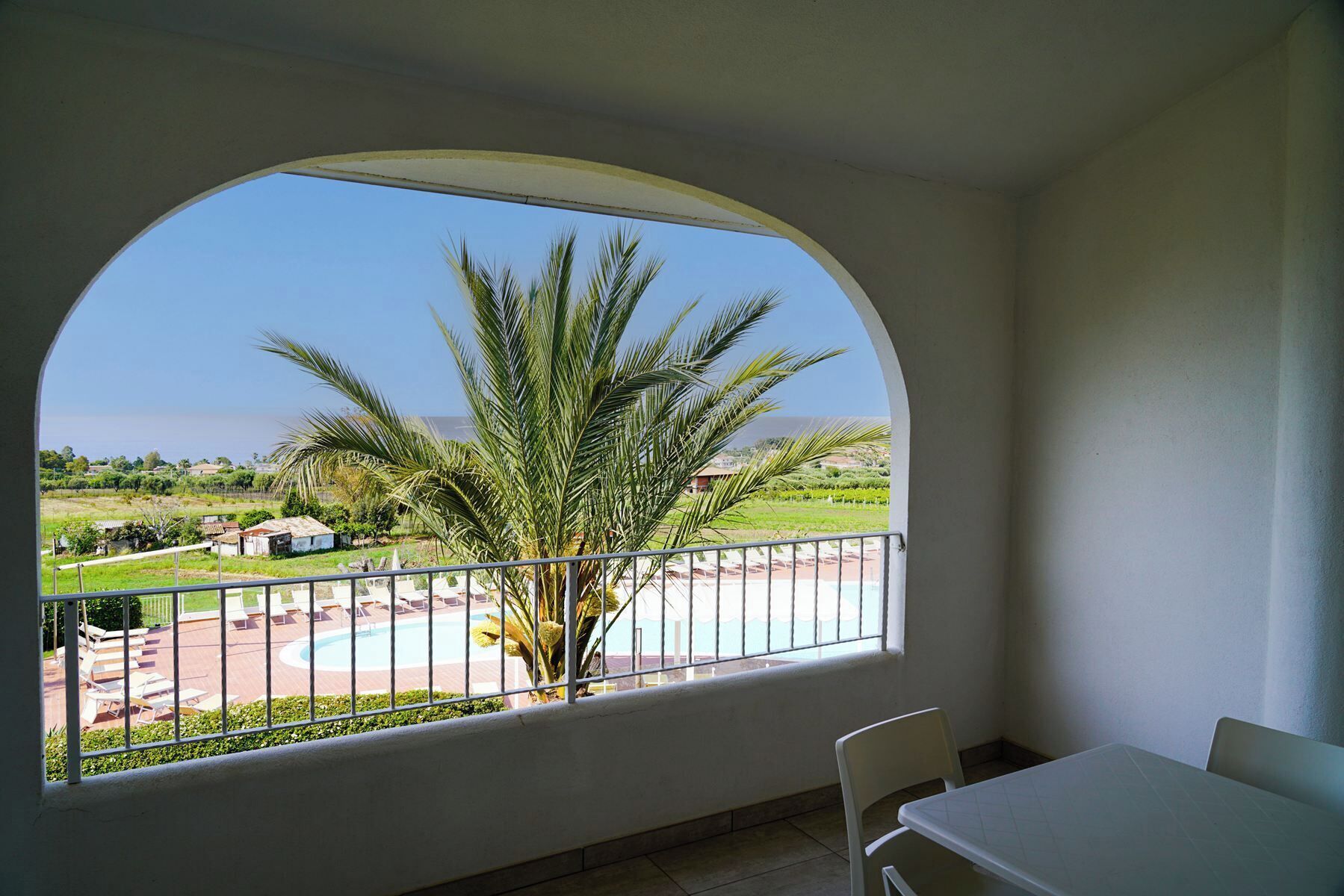 A balcony with a view of a swimming pool and palm trees.