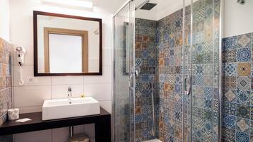 Une salle de bain avec un lavabo blanc, un miroir et une douche aux carreaux décorés.