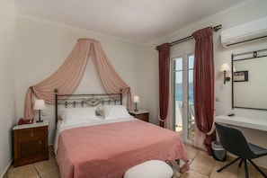 A bedroom with a bed, bedside tables, a desk, and a chair. - Ostria Hotel-milos (Milos)