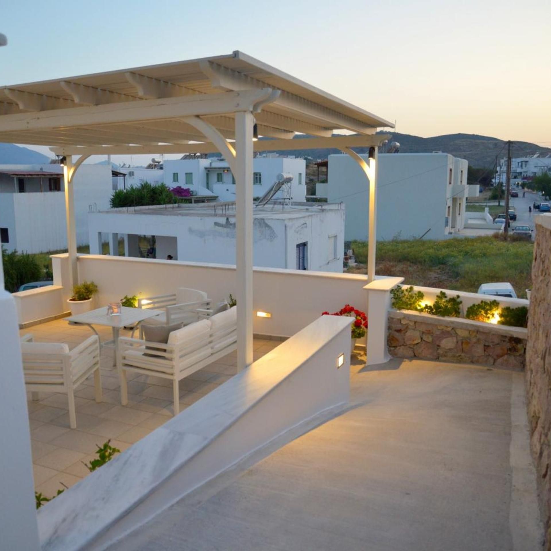 Eine Dachterrasse mit einer Pergola, einer Sitzgelegenheit und Blick auf die umliegenden Gebäude.
