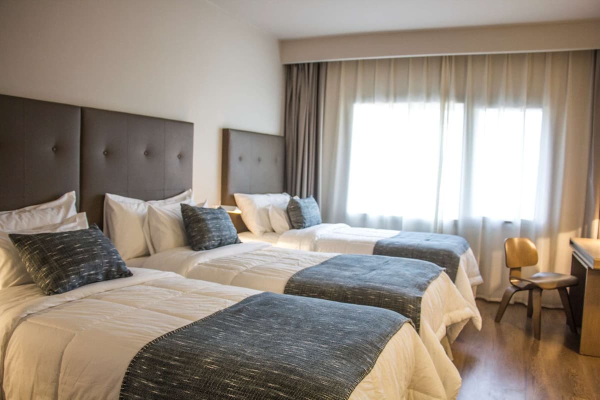 A hotel room with two beds, a desk, and a chair.