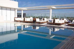 Una piscina al aire libre, sillones reclinables de piscina