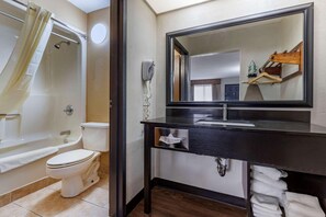 A bathroom with a bathtub, toilet, and a vanity with a mirror. - Quality Inn and Suites Ft Jackson Maingate (Columbia)