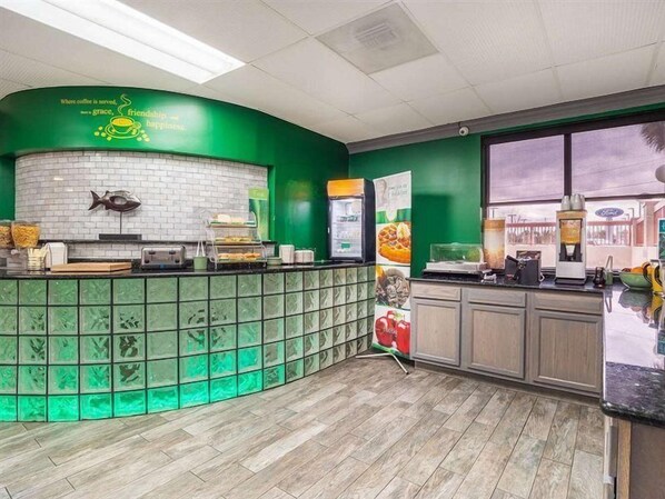 A kitchen area with a green and white color scheme, a fish decoration on the wall, and a coffee machine. - Quality Inn and Suites Ft Jackson Maingate (Columbia)