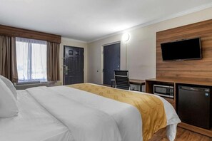 A hotel room with a bed, a desk, a television, and a microwave. - Quality Inn and Suites Ft Jackson Maingate (Columbia)