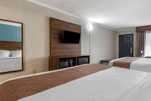 A hotel room with two beds, a flat-screen TV mounted on a wooden panel, a microwave, and a small table. - Quality Inn and Suites Ft Jackson Maingate (Columbia)