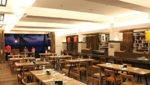Un restaurante con varias mesas y sillas, una zona de bar y un escenario con un telón de fondo.