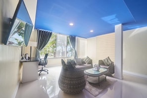 Una habitación moderna con escritorio, silla de oficina, sofá y dos mesas redondas.
