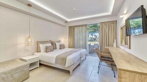 Un dormitorio moderno con una cama grande, mesitas de noche, un escritorio y un televisor.