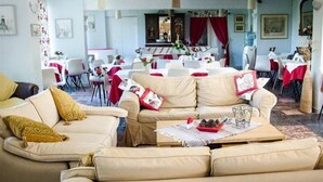Una sala de estar acogedora con un sofá color beige, una mesa de centro con adornos y un comedor con manteles rojos y blancos.
