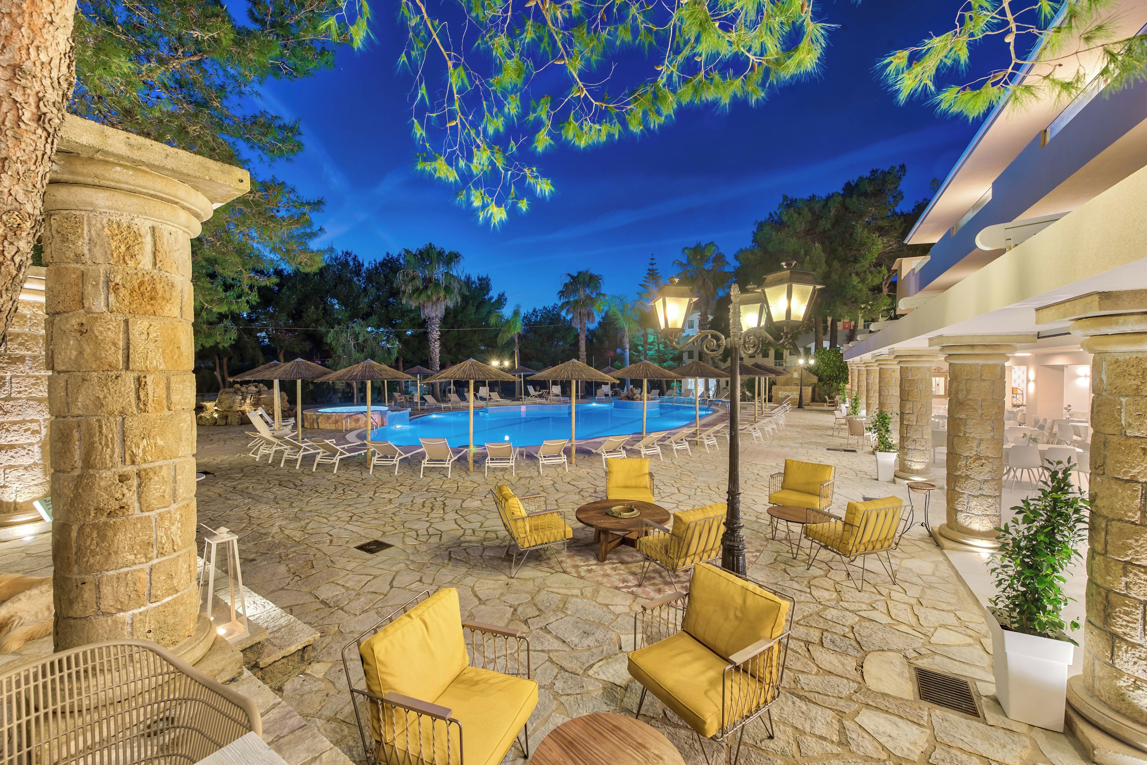 A poolside area with lounge chairs, a pool, and stone flooring.