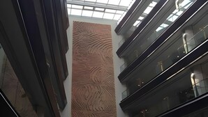 A modern interior with a central textured wall, glass railings, and a skylight.