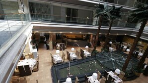 A multi-level restaurant with tables and chairs arranged around a central water feature. - Dazhong Airport South (Shanghai)